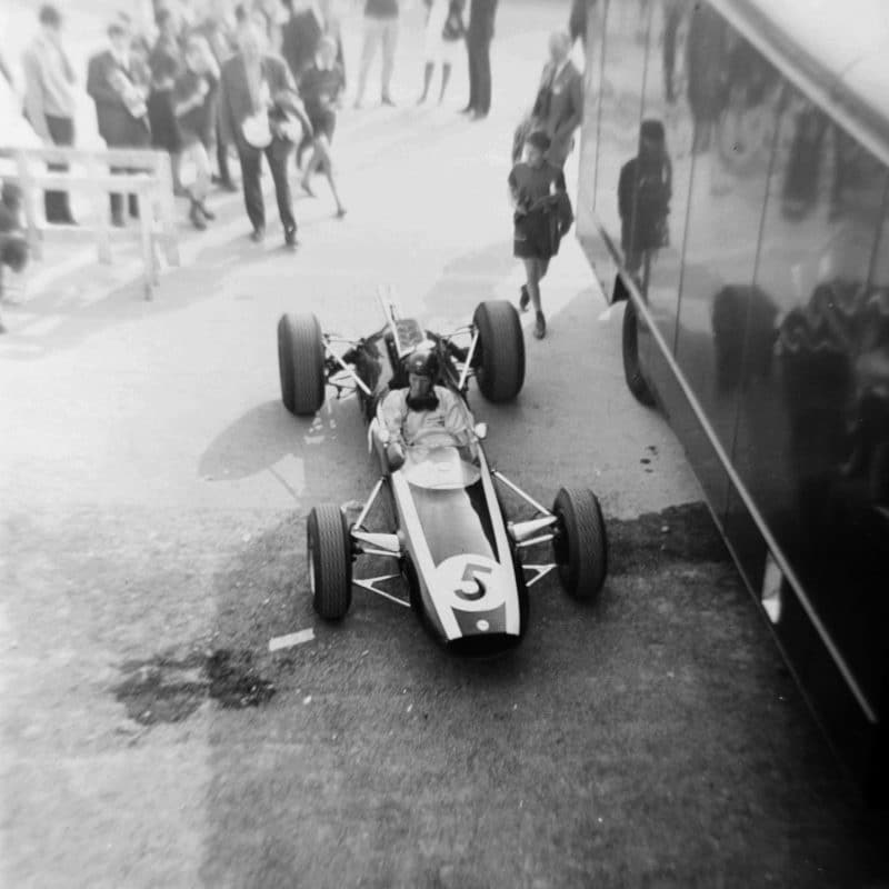 Jochen Rindt in Cooper drives through the paddock at the 1965 Belgian Grand Prix